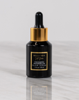 Black serum bottle of Bella Vida Santa Barbara luxury skincare Cocomero Watermelon Glow Serum with hyaluronic acid with gold cap on a light gray background