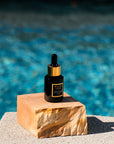 black Bella Vida Santa Barbara luxury skincare bottles with gold caps . Sunlight Serum, by pool