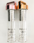 two glass water bottles by Bella Vida Santa Barbara one with gold lid one with pink lid