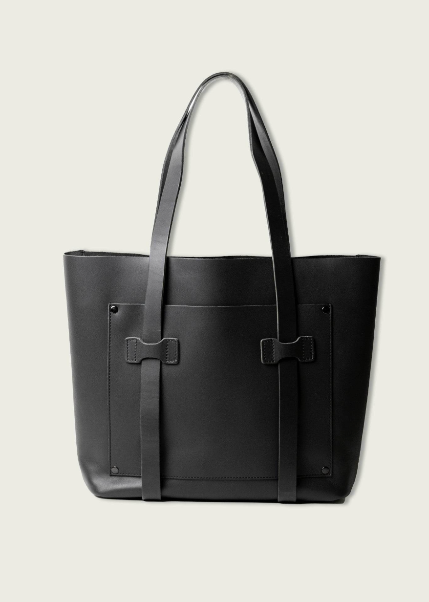 Black leather tote bag with a bow detail on a light gray background