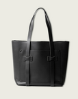 Black leather tote bag with a bow detail on a light gray background