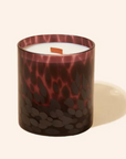 Candle in a decorative glass container with a pattern on a white background